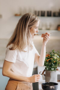 Vrouw neemt een hap van een ayurvedische maaltijd – moment van zelfzorg en bewust eten zonder schuldgevoel